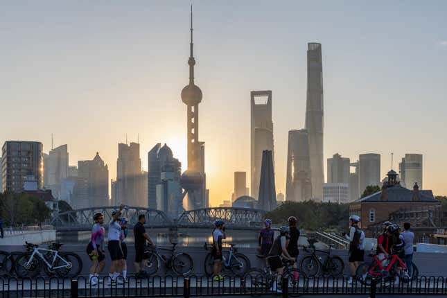 FILE - In this photo released by Xinhua News Agency, cyclists, some take selfie as they take rest against the sunrise skylines in Pudong, China&#39;s financial and commercial hub, in Shanghai, China on Friday, Nov. 3, 2023. Credit rating agency Moody’s cut its outlook for Chinese sovereign bonds to negative on Tuesday, Dec. 5, 2023, citing risks from a slowing economy and a crisis in its property sector.(Wang Xiang/Xinhua via AP, File)