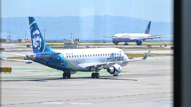 alaska airline jet sitting on airport tarmac opposite a united plane in the background.