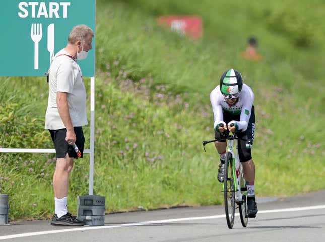 Patrick Moster, Sports Director of the BDR (German Cycling Federation), stands on the side of the track next to Azzedine Lagab from Algeria in action during the time trial. 