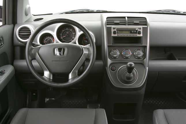 A view from the driver's perspective of a 2004 Honda Element with a manual mounted on the dash