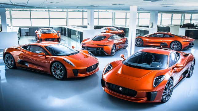 A photo of six orange Jaguar supercars parked in a warehouse. 