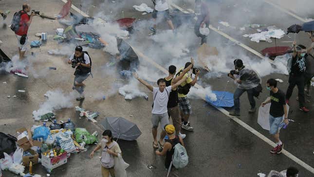 Protesters walk through tear gas used by riot police against protesters after thousands of people blocked a main road at the financial central district in Hong Kong, Sunday, Sept. 28, 2014