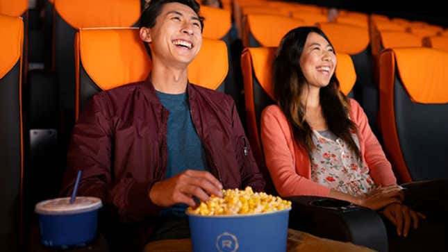 Two moviegoers in a theater enjoying a tub of Regal Cinemas popcorn