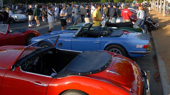 A photo of cars lined up at a cars & Coffee meet. 