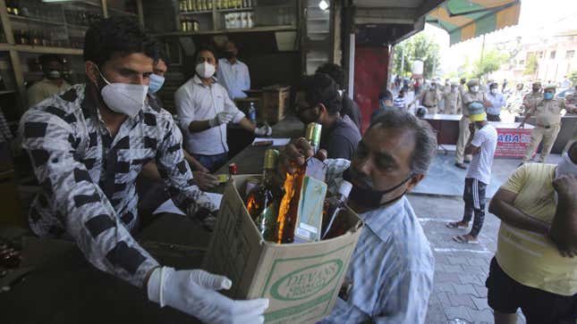 A man buys bottles of liquor outside a wine store during a nationwide lockdown to curb the spread of new coronavirus in Jammu, India, Friday, May 22, 2020.