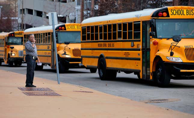 FILE - Yvette Lewis, a Metro High School security guard, watches as a fleet of Missouri Central Bus Company school busses leaves the school following dismissal, Tuesday, Feb. 27, 2024, in St. Louis, Mo. Missouri Central School Bus Co. will end its contract with St. Louis Public Schools, Tuesday, March 26, a year early, bringing an end to a relationship strained after a bus driver “sickout” prompted by a noose left at the workstation of a Black mechanic in February.(Christian Gooden/St. Louis Post-Dispatch via AP)