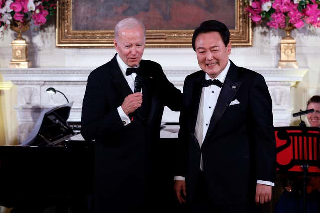 Joe Biden and Yoon Suk Yeol wearing black suit and tuxedo standing beside each other