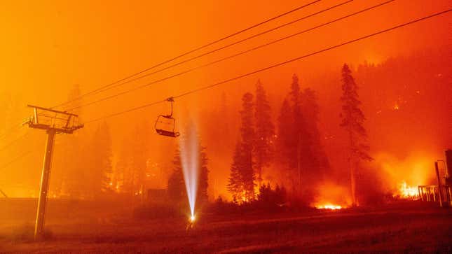 A photographer shines a flashlight towards a chair lift as flames surround Sierra-at-Tahoe Resort during the Caldor Fire in Twin Bridges, California.