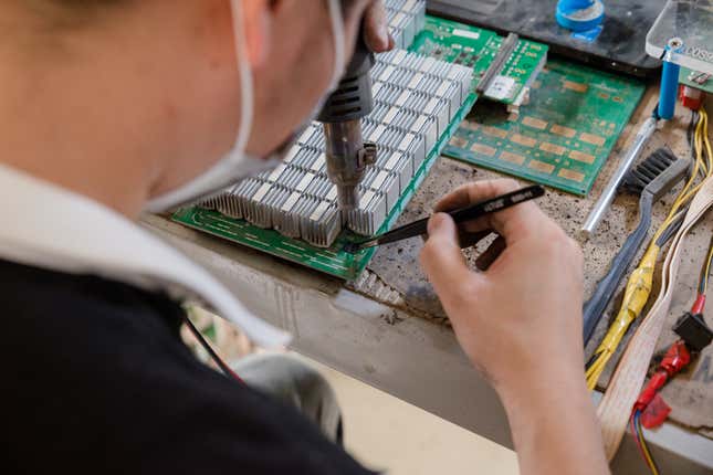 A worker fixes a component on a mining machine.