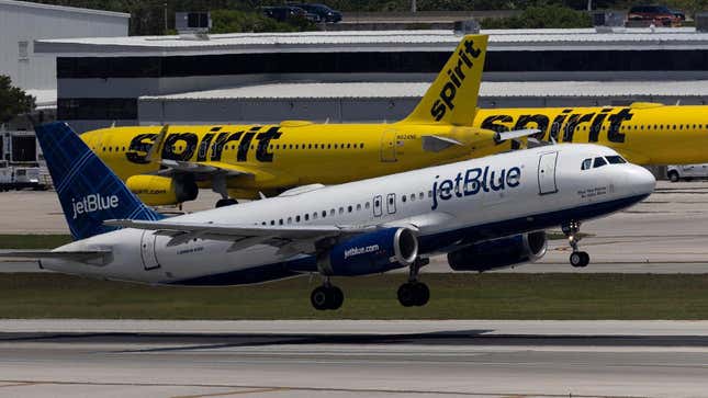 A JetBlue Airlines plane takes off near Spirit Airlines planes.