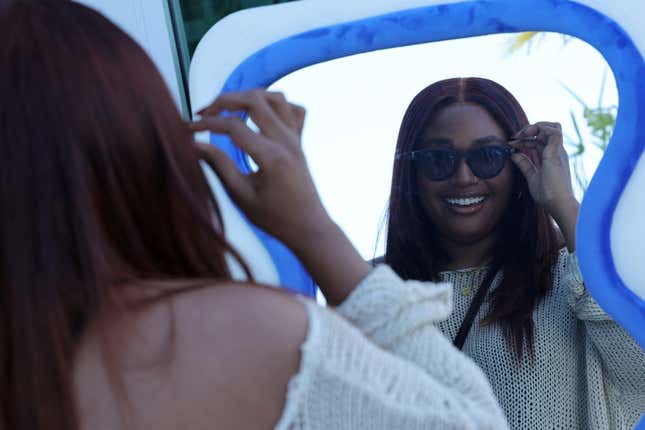 Woman smiling at herself in mirror wearing Ray Ban Meta wayfarer style sunglasses
