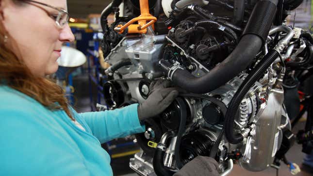 A photo of someone fitting an engine belt to a car. 