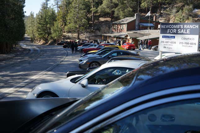 A large gathering of cars and people are parked at Newcomb's Ranch in the Angeles National Forest.