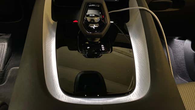 A close-up of the center console and the warm, gentle light that emanates from around the shifter mechanism and illuminates the pale wood. 