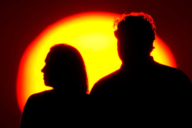 FILE - A couple watches the sun set from a park, July 10, 2021, in Kansas City, Mo. After a spouse dies, the survivor’s financial situation often changes for the worse. Social Security benefits can drop. Tax rates go up (known as the “widow’s penalty”). Pension income may fall or disappear entirely. The longer the survivor lives, the worse their financial position may become. Some survivor penalties can’t be avoided, but good planning can reduce their impact. (AP Photo/Charlie Riedel, File)