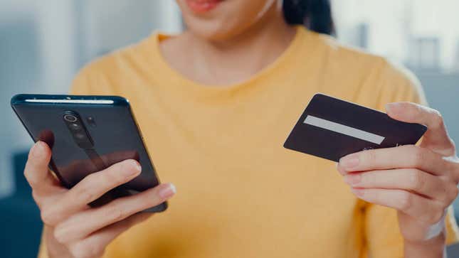 A photo shows a woman using a credit card to buy something on her phone. 