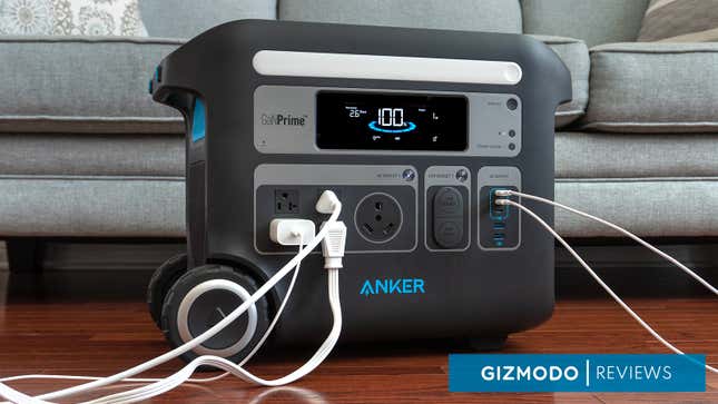 The Anker PowerHouse 767 Portable Power Station sitting in front of a sofa with several cords plugged into it.
