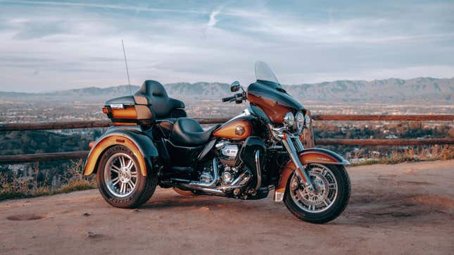 A rustic looking brown Harley motorized tricycle parked in front of a vista