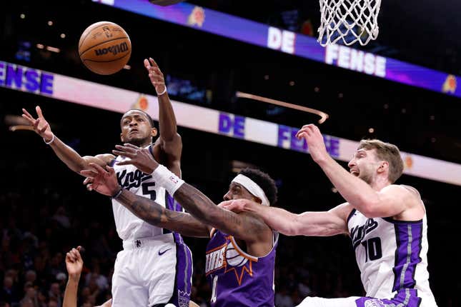 PHOENIX, ARIZONA - FEBRUARY 13: Royce O'Neale #00 of the Phoenix Suns attempts to control a rebound against Domantas Sabonis #10 and De'Aaron Fox #5 of the Sacramento Kings during the first half at Footprint Center on February 13, 2024 in Phoenix, Arizona. NOTE TO USER: User expressly acknowledges and agrees that, by downloading and or using this photograph, User is consenting to the terms and conditions of the Getty Images License Agreement. (Photo by Chris Coduto/Getty Images)