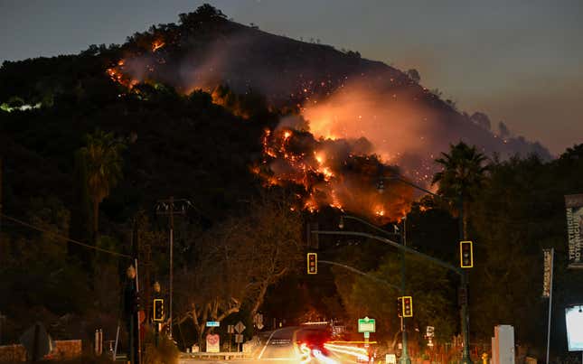 LOS ANGELES, CALIFORNIA - JANUARY 9: A view of flames at the mountain as seen from Topanga Canyon near Pacific Palisades in Topanga, Los Angeles, California, United States on January 9, 2025. A fast-moving wildfire has forced 180,000 people to evacuate, with officials warning that worsening winds could further escalate the blaze. 