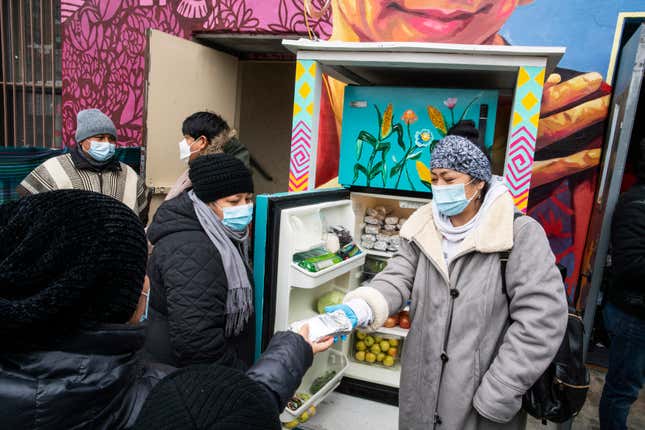 FILE - Volunteers pass out information on the COVID-19 vaccine as people receive food from the 24-hour community fridge at the community center Mixteca during the coronavirus pandemic, Feb. 13, 2021, in the Brooklyn borough of New York. The share of Latinos who give to established charities has dropped sharply since 2008, a new study has found. The same has been true for other Americans, but the percentage of Hispanics who give to help people in need through less formal efforts is higher than for others in the United States. (AP Photo/Eduardo Munoz Alvarez, file)