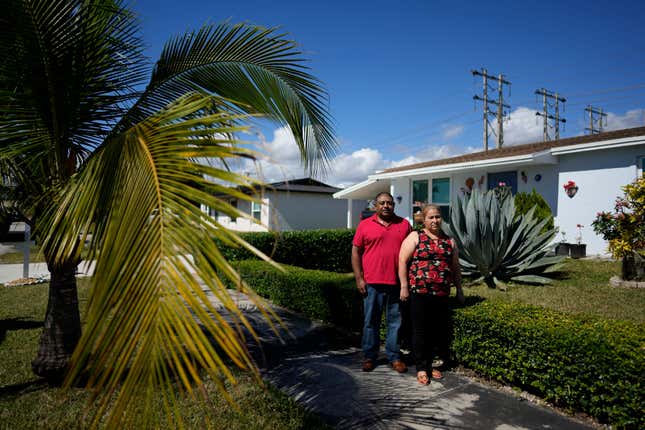 Rosalinda Ramirez, 57, and her partner Jose Guerrero, 41, Mexican immigrants who crossed the border separately over two decades ago and who have built lives and he a landscaping business in the U.S. but never found a route to obtain legal status, pose for a picture outside their home in Homestead, Fla., Tuesday, Nov. 7, 2023. The couple are among those longterm immigrants in the U.S. who are frustrated to see newer arrivals getting work permits and government assistance, while they have paid taxes for decades without earning work permits, the ability to visit relatives back home and return, or freedom from the fear of deportation. (AP Photo/Rebecca Blackwell)