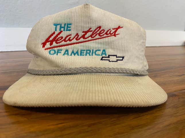 A cream Chevrolet "The Heartbeat of America" hat on a wood surface