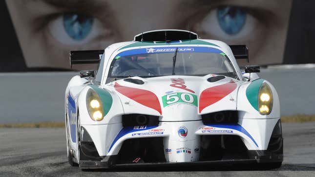 A photo of a white, green and red Panoz racing car on track. 