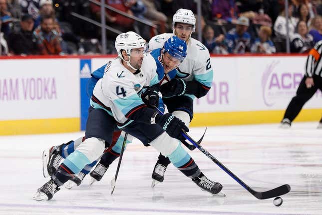 Nov 9, 2023; Denver, Colorado, USA; Seattle Kraken defenseman Justin Schultz (4) controls the puck under pressure from Colorado Avalanche right wing Mikko Rantanen (96) as center Alex Wennberg (21) looks on in the second period at Ball Arena.