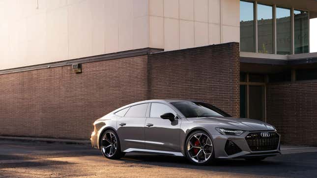 A gray Audi RS7 parked in front of a brick building