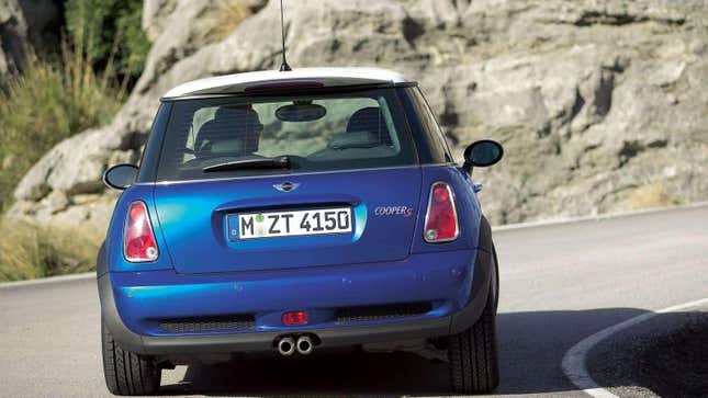 A blue R53 Mini Cooper S driving around a curve from the rear
