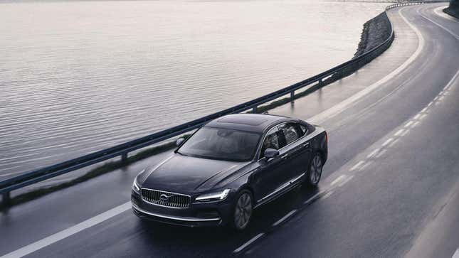 Une Volvo S90 noire circulant sur une route sinueuse près de l’eau