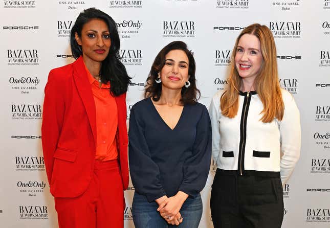 three women standing side by side in front of a white backdrop that has BAZAAR logos all over it