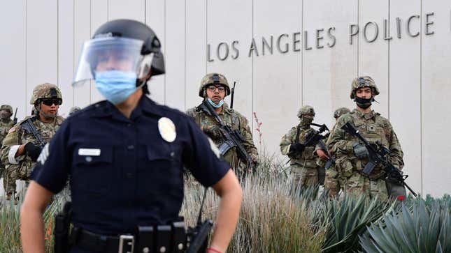 A police officer stands with armed members of the National Guard facing protesters marching over the death of George Floyd on June 1, 2020 in Los Angeles, California.