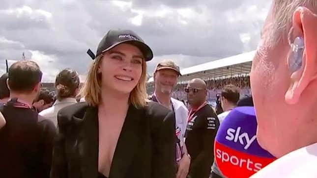 Cara Delevingne smiles as she declines an interview with Sky Sports F1 presenter Martin Brundle