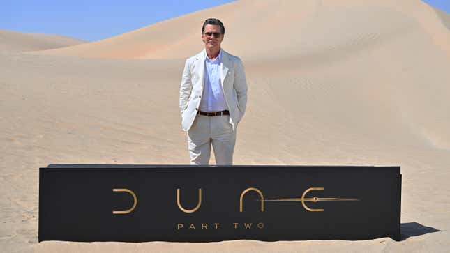Josh Brolin on a sand dune behind a Dune: Part Two sign
