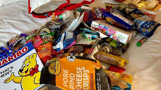 Hotel bed strewn with tons of candy and snack packages
