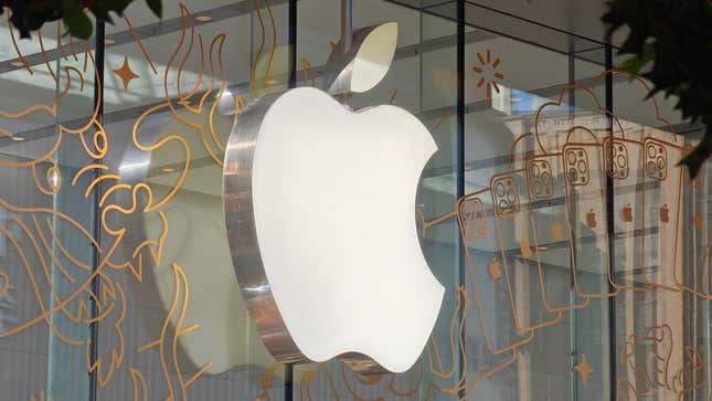 The Apple logo is being displayed on a glass window with outlines of a dragon and iPhones in gold.