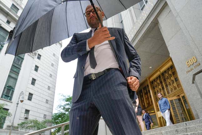 Gerald Shvartsman, hides from photojournalists using an umbrella after exiting Federal Court, Thursday, July 20, 2023, in New York.