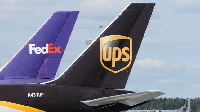 The tail fin of a UPS plane in front of the tail fin of a FedEx plane