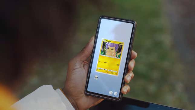 A player holds their phone and looks at Pikachu card.
