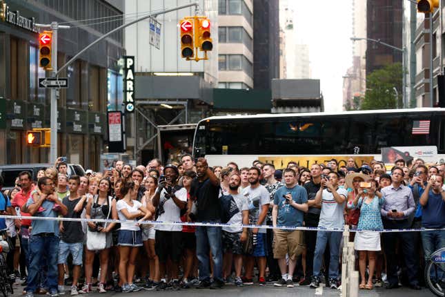 Pedestrians gather to watch as officers from the NYPD monitor a man as he climbs the outside of Trump Tower in New York