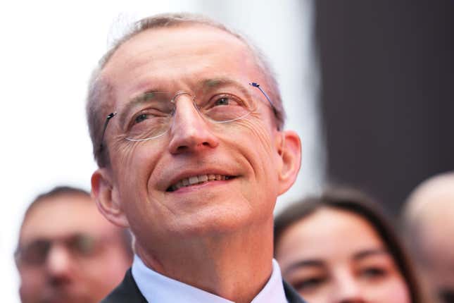 Pat Gelsinger portant des lunettes souriant regardant vers le haut avec des personnes floues derrière lui