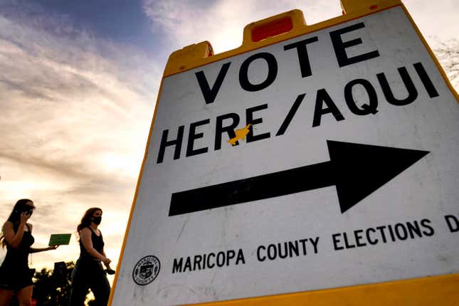 Voters deliver their ballot to a polling station in Tempe, Ariz., on Nov. 3, 2020. The U.S. Department of Justice on Tuesday, July 5, 2022, sued Arizona over a new law requiring people who use a federal form to register to vote to provide additional proof of citizenship if they want to vote for president or using the state’s popular vote-by-mail system.