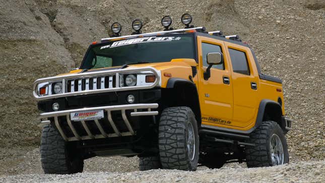 A yellow Hummer H2 parked on gravel. 