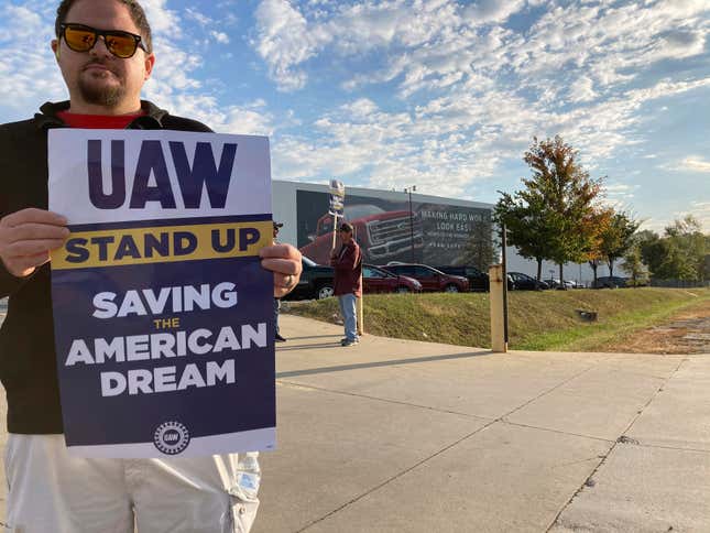 A union worker at Ford holds a sign as strikers surround the Kentucky Truck Plant in Louisville, Ky., Thursday, Oct. 12, 2023. About 8,700 workers went on strike at the massive plant Wednesday night, joining other auto workers around the country who have been on picket lines for weeks. (AP Photo/Dylan Lovan)