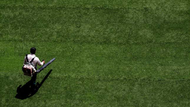 An overhead view of a groundskeeper walking with a leafblower.