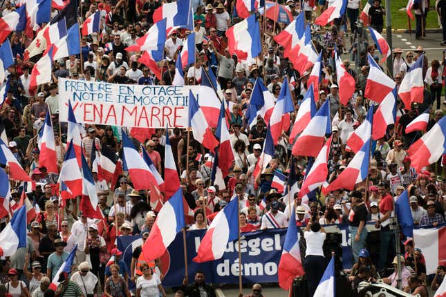Demonstrators from several loyalist parties wave French national flags  and hold a banner reading “Prendre en otage notre democratien y’en a  marre” (Take our democracy away from you) as they march during a  demonstration to support the enlargement of the electorate for the  forthcoming provincial elections in New Caledonia, in Noumea, on April  13, 2024. 