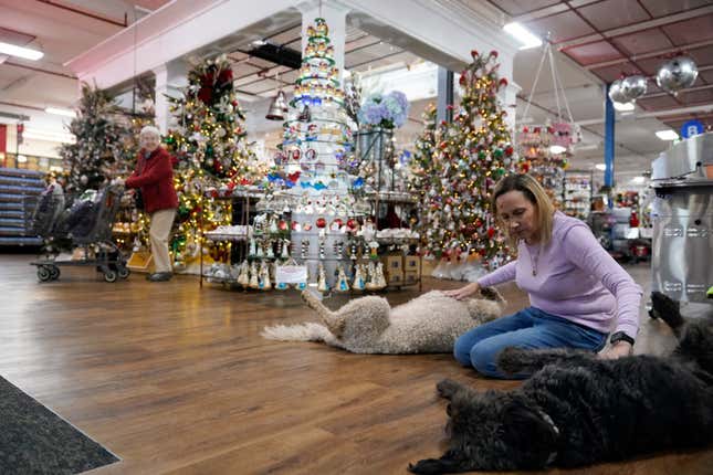 Blackhawk Hardware employee Jenny Stenhouse, right, pets the dogs of the store&#39;s co-owner, which are typically seen at the entrance, Wednesday, Nov. 1, 2023, in Charlotte, N.C. Holiday entertaining is back this year, and the store is seeing an influx of shoppers buying place settings, ornaments and indoor decorations. (AP Photo/Erik Verduzco)