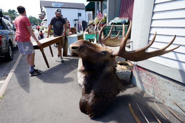 FILE - Two men carry a table into Camp Camp Moosehead Lake Indian Store, a gift shop and vintage store, Saturday, Aug. 15, 2020 in York Beach, Maine. Maximalism is a design trend emphasizing more color, texture and one-of-a-kind pieces. However, filling your home with ample layers of eye-catching decor can feel intimidating and seem expensive. To avoid maxing out your budget, shop at vintage stores and estate sales for unique finds. (AP Photo/Robert F. Bukaty, File)